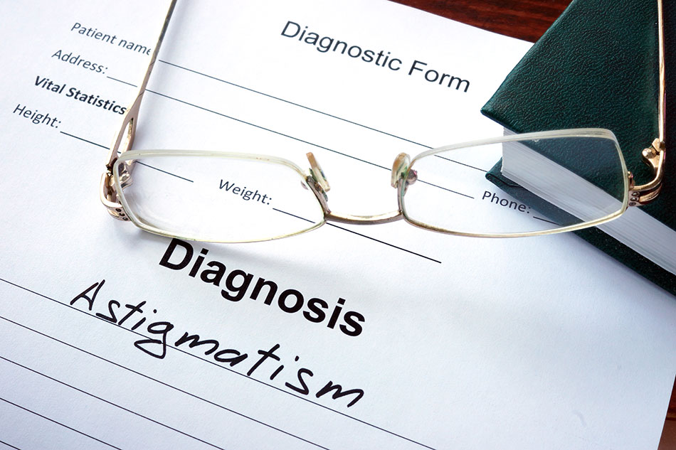 pair of glasses lying on Diagnosis form with word Astigmatism written on it