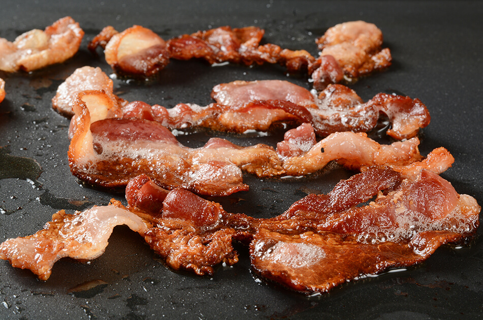 slices of bacon on a hot grill