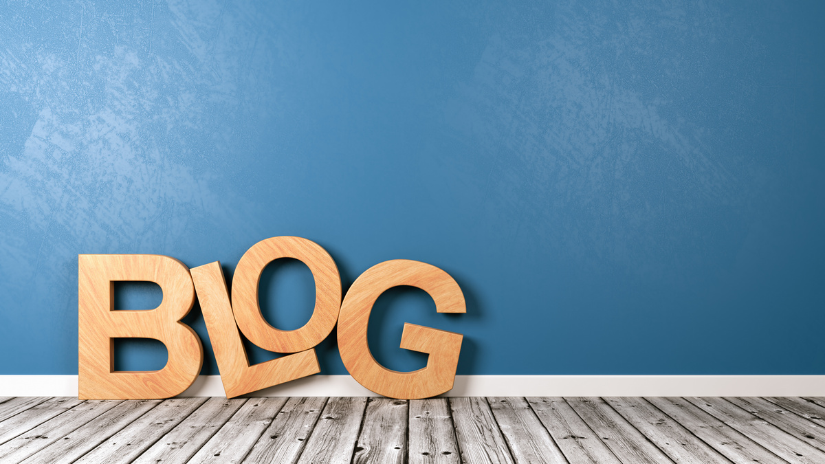“Blog” in wooden letters on a wooden floor and blue background