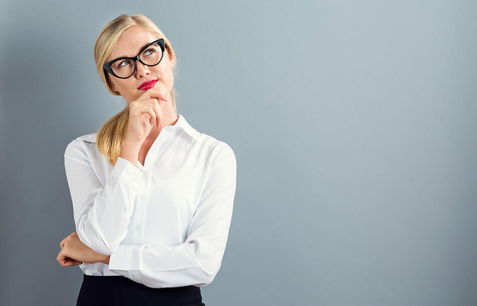 blonde woman in white blouse with black glasses on in a thoughtful pose