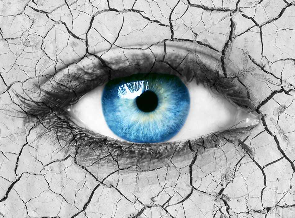 Woman’s blue eye over dry cracked ground