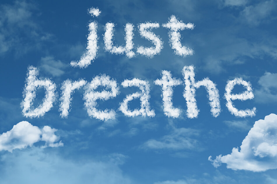 blue sky and clouds with just breathe written in white smoke