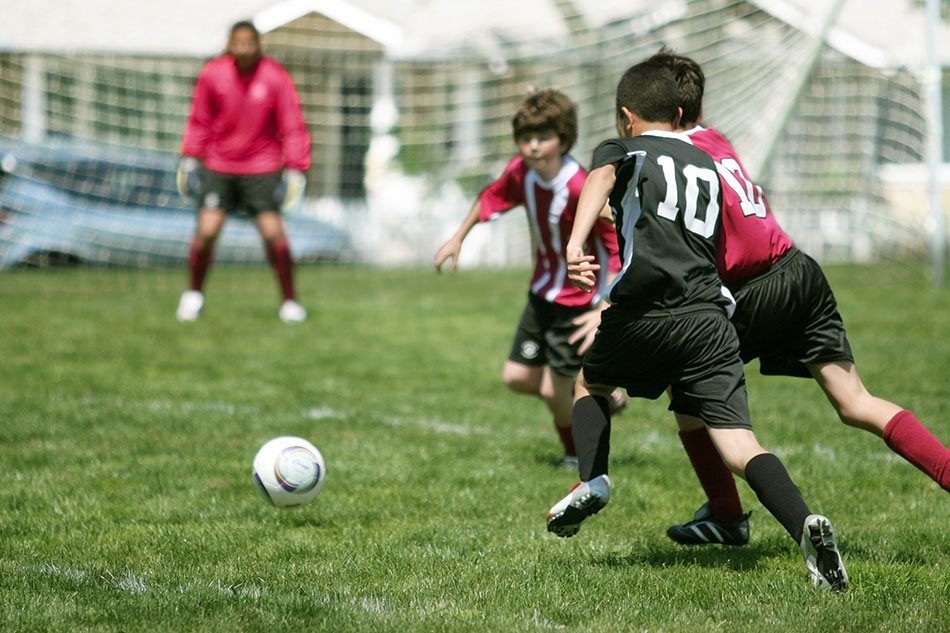 boys playing soccer in red and black uniforms