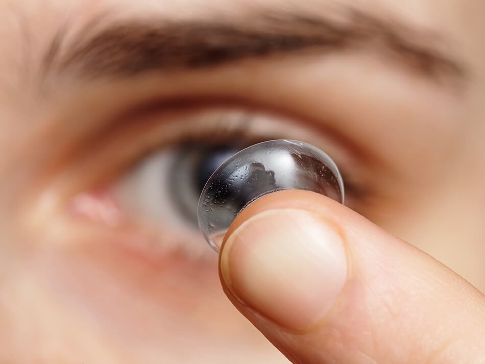 close up of man inserting contact lens in his eye