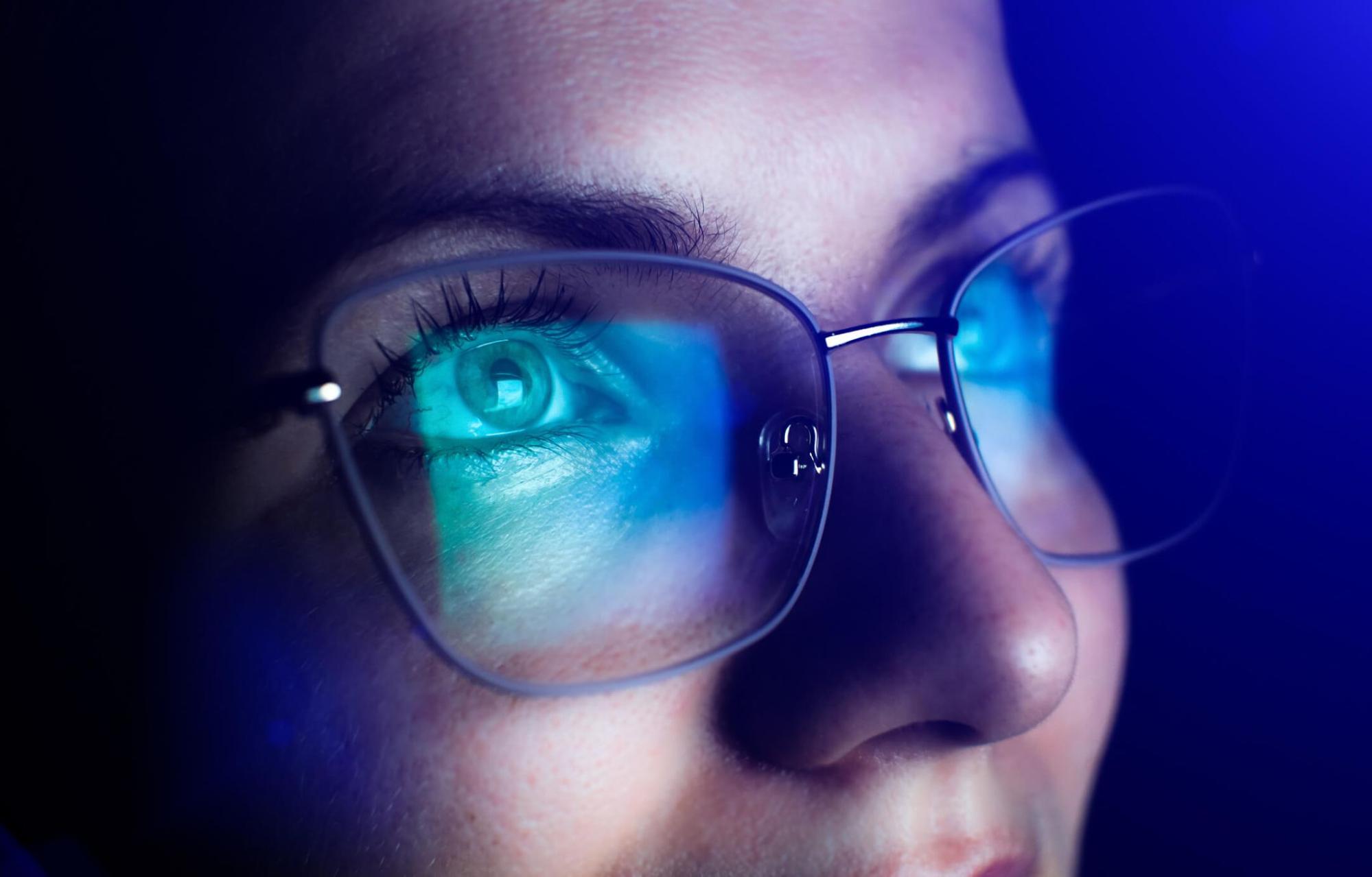 close-up of eye with glasses reflecting blue light