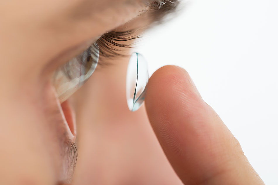 Close-up of a man inserting a contact lens in his eye