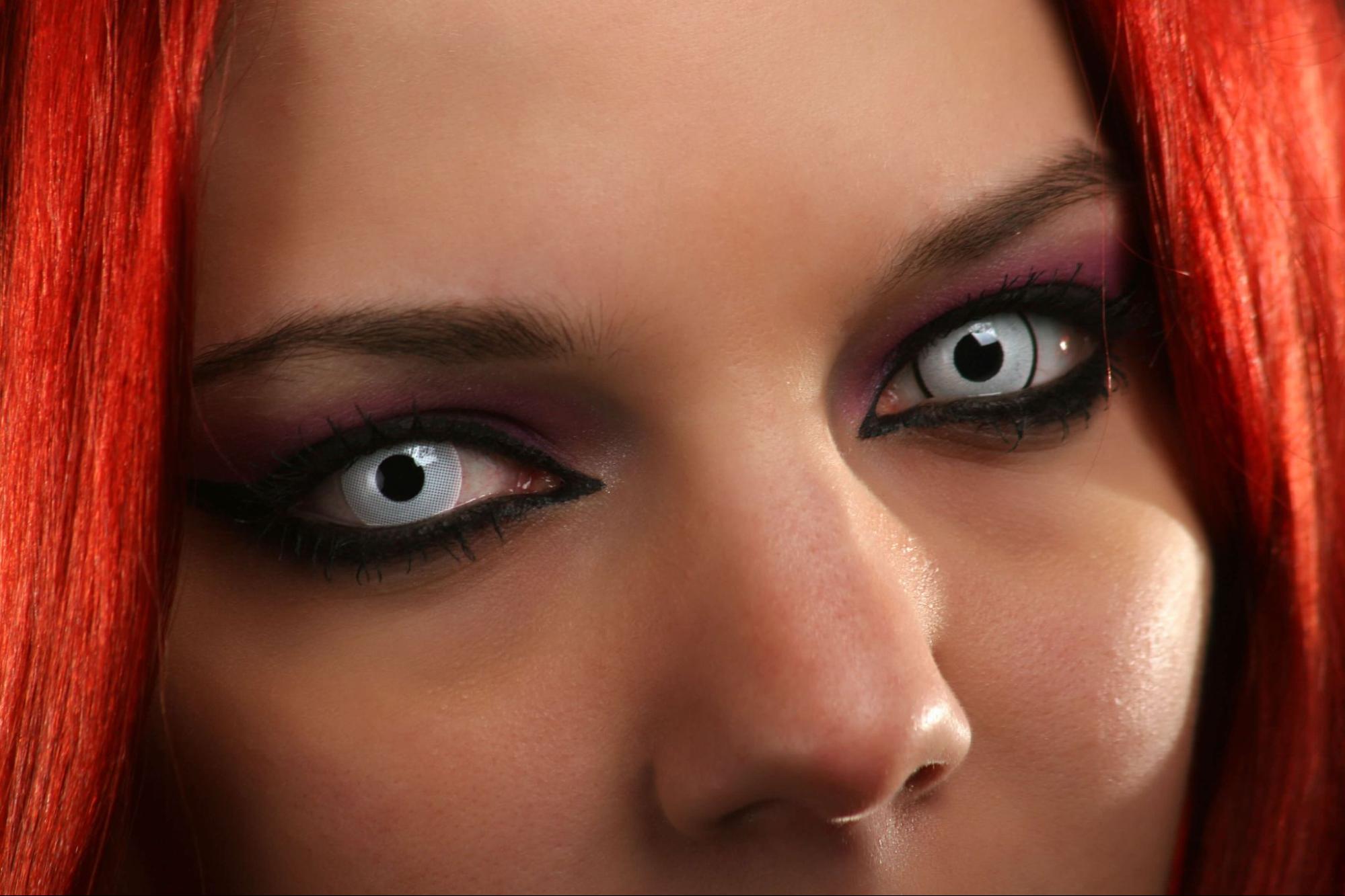 Cosplayer wearing white special-effect colored contacts with red wig and dramatic eye makeup