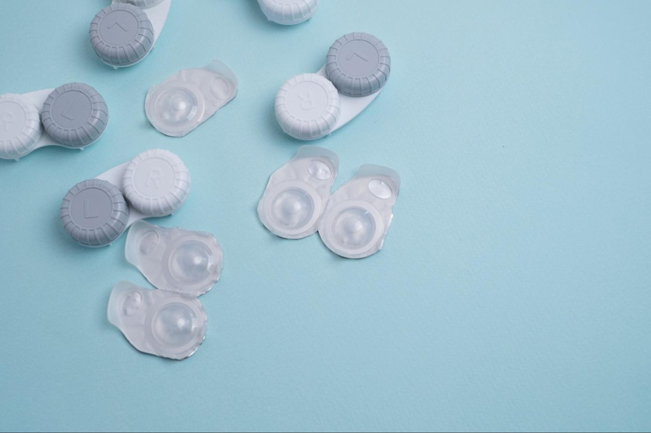 Contact lens cases and lenses on a pastel blue background