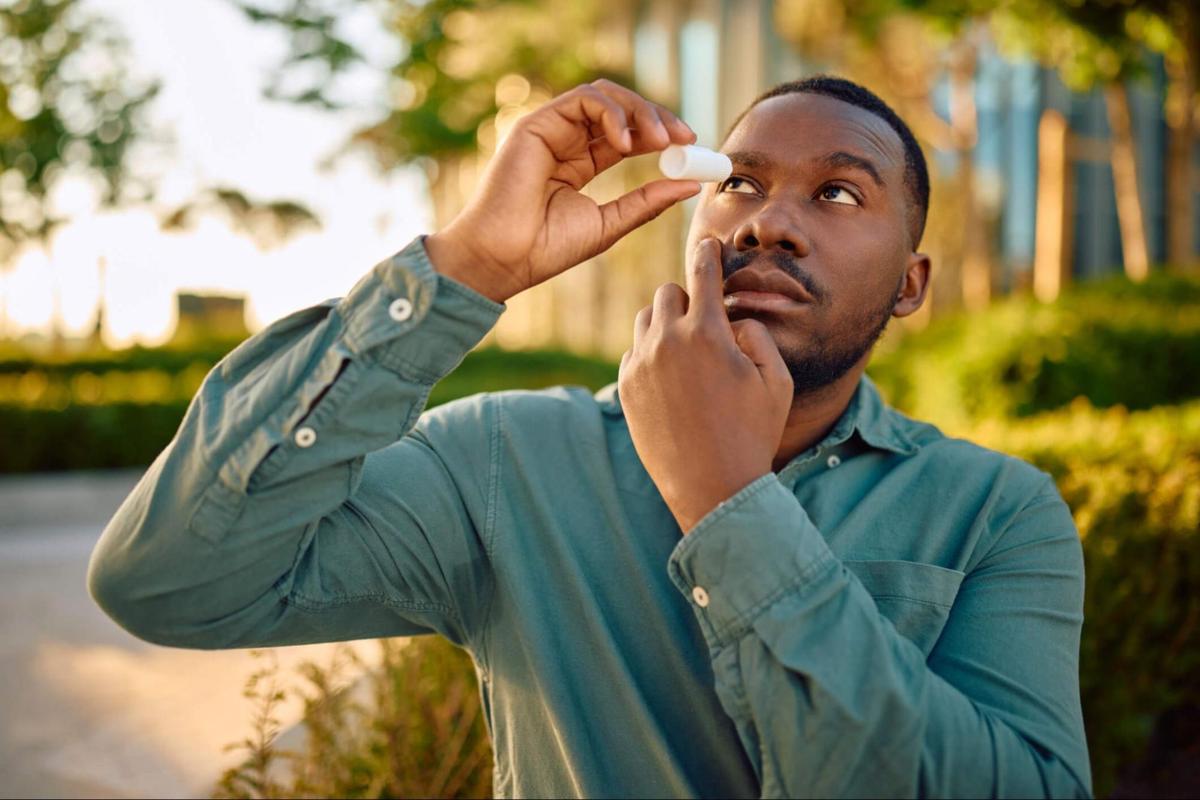 Man applying eye drops before wearing contact lenses outdoors