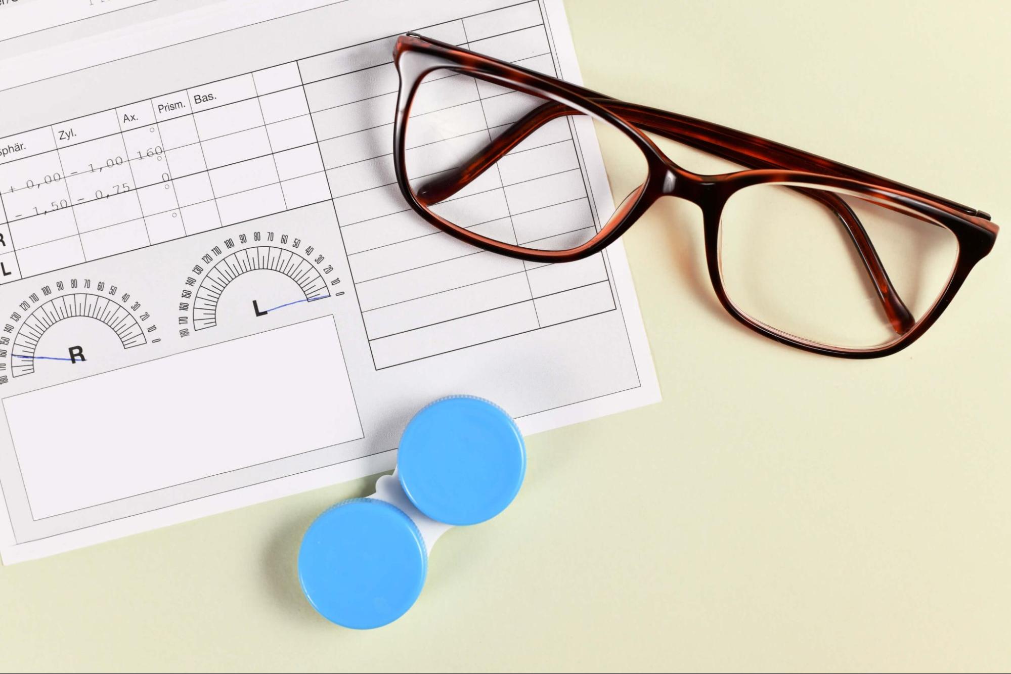Contact lens prescription form next to glasses and a lens case