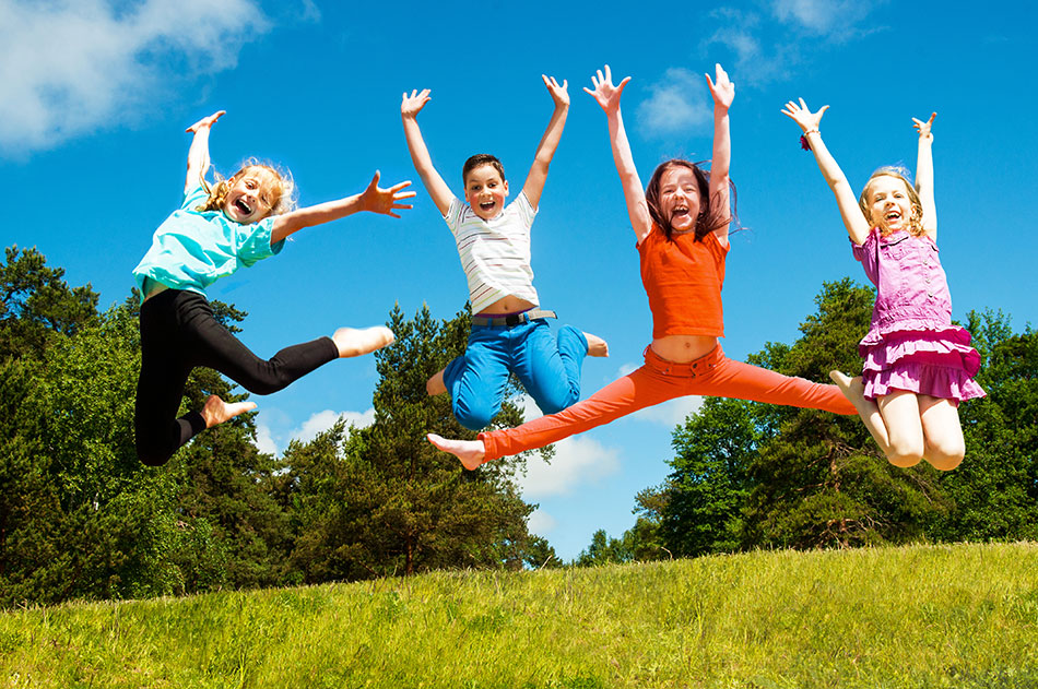 Four children jumping for joy in field