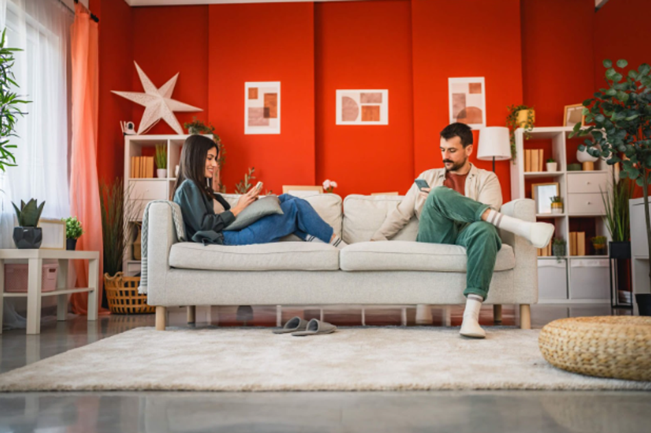 Couple sitting on a sofa at home using smartphones in a living room