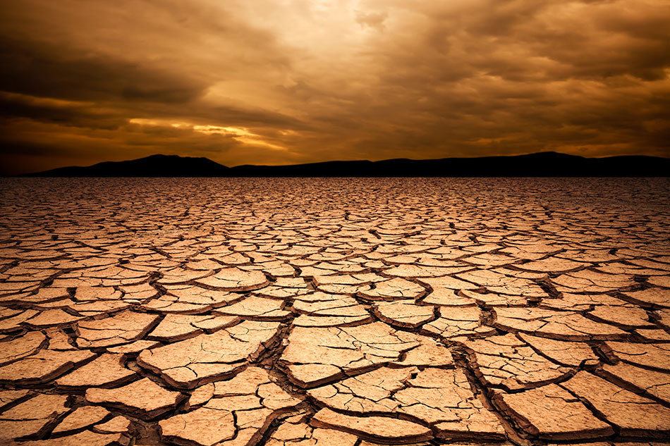 dry and cracked desert scene with mountain range in the background