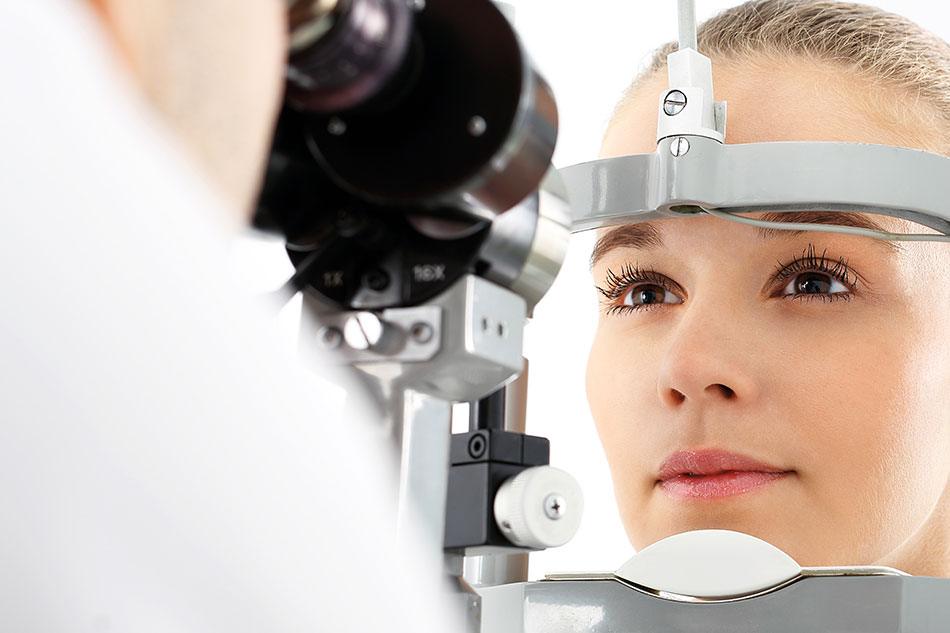 eye doctor looking into woman patient’s eyes with a machine