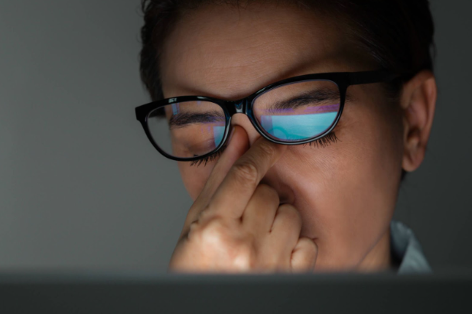 Close-up of a person wearing glasses experiencing eye strain from screen exposure