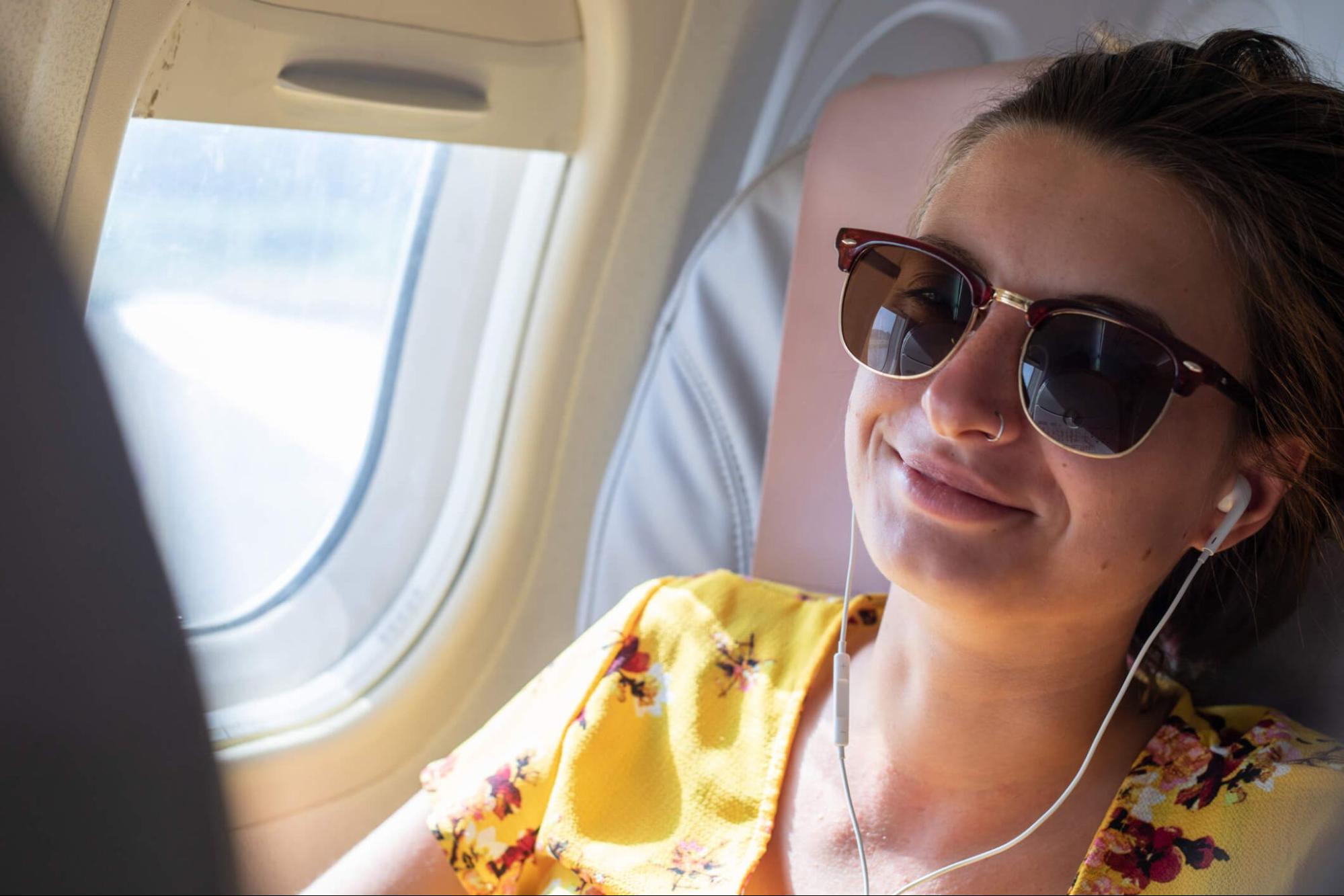 A female traveler wearing sunglasses for eye protection on an airplane flight