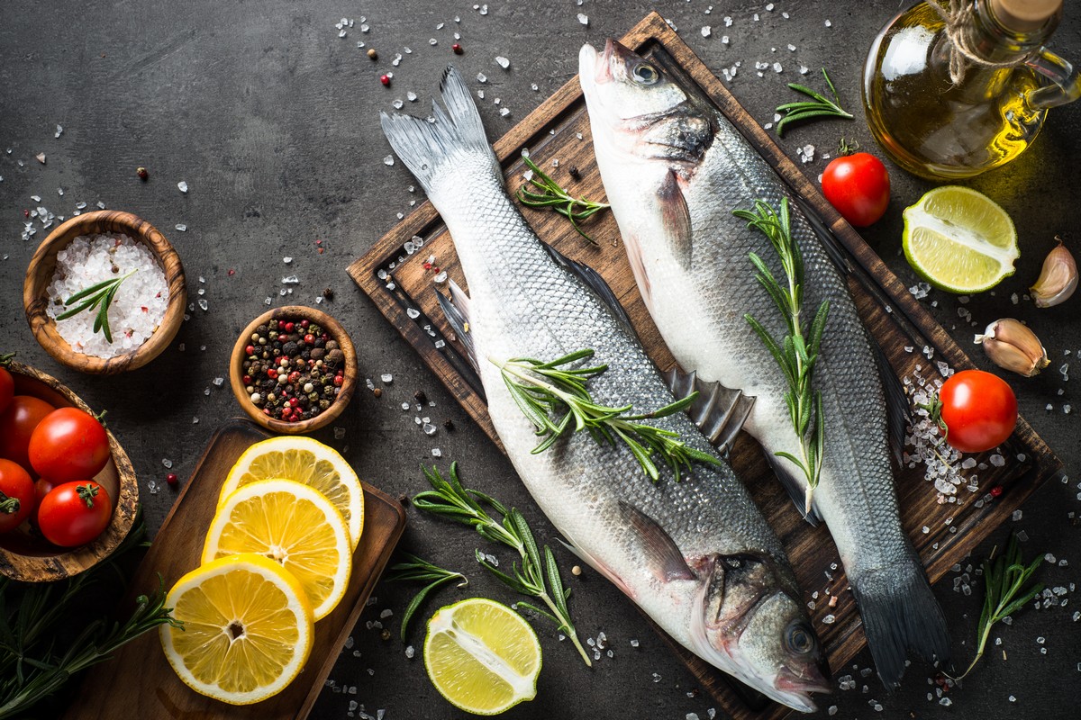 fresh fish on wood board with spices and citrus fruits