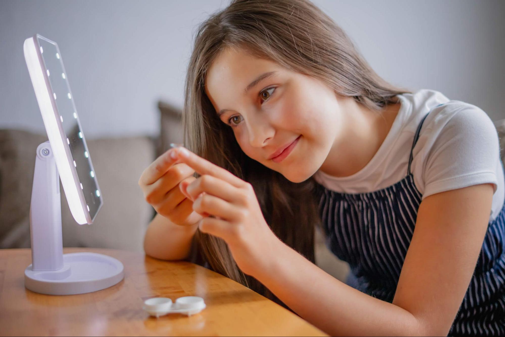 Girl inserting contact lenses for myopia treatment