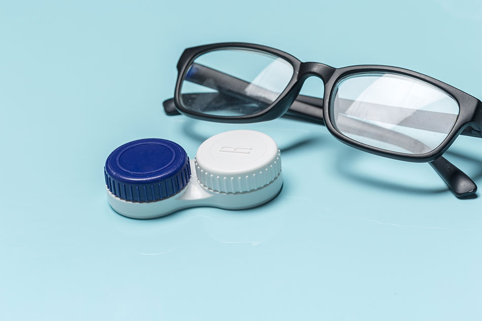 glasses and contact case on light blue background