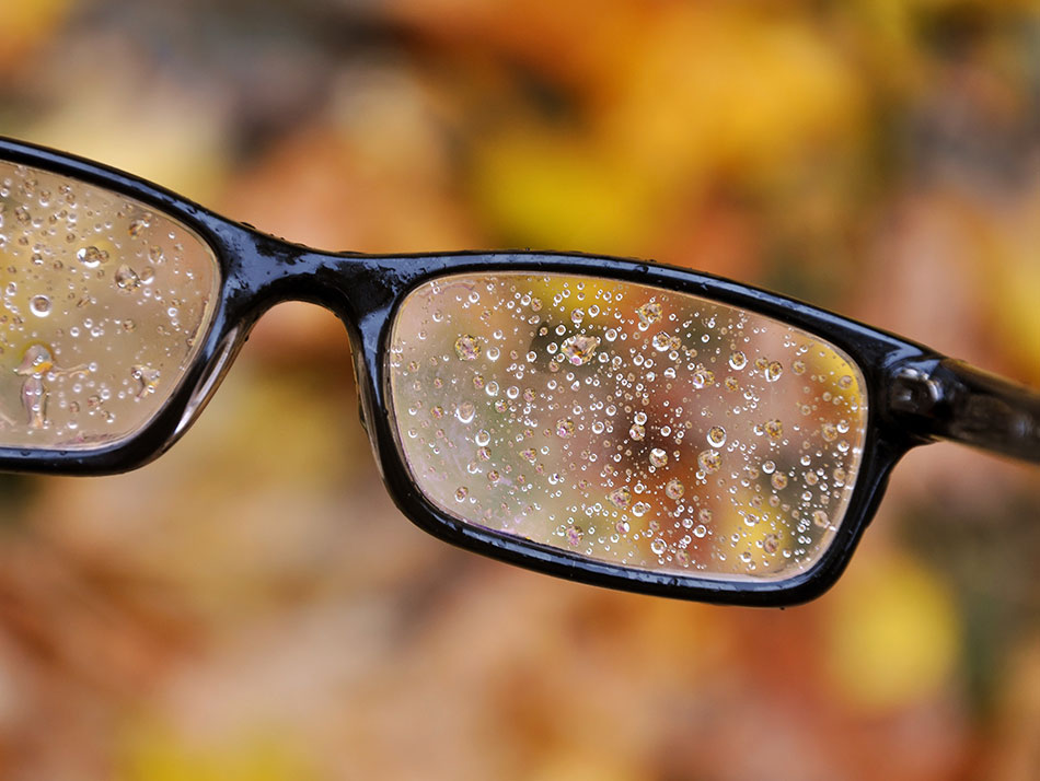 Glasses full of raindrops, leaves in background