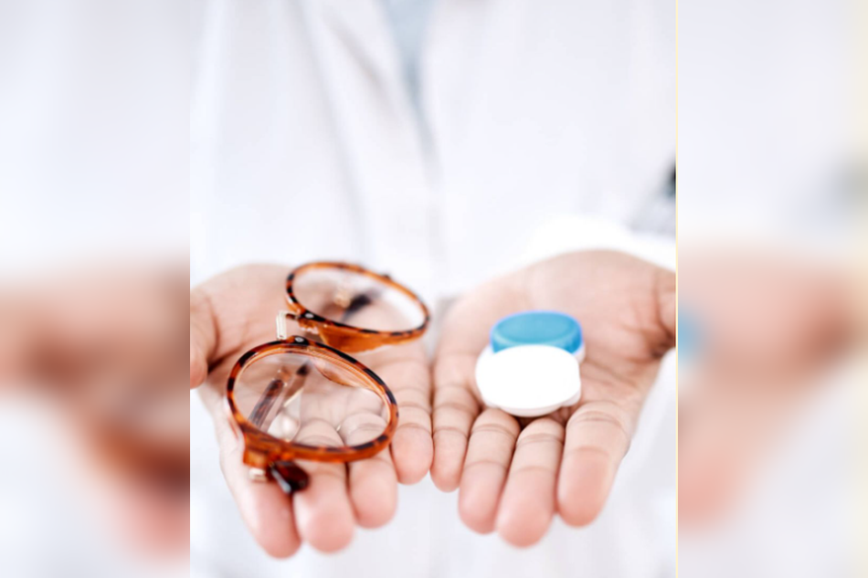 Hands holding eyeglasses and a contact lens case for vision correction comparison