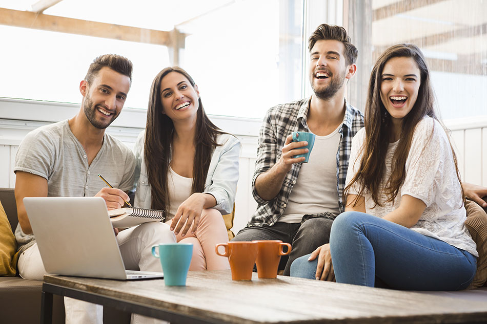 4 happy men and women having coffee and working