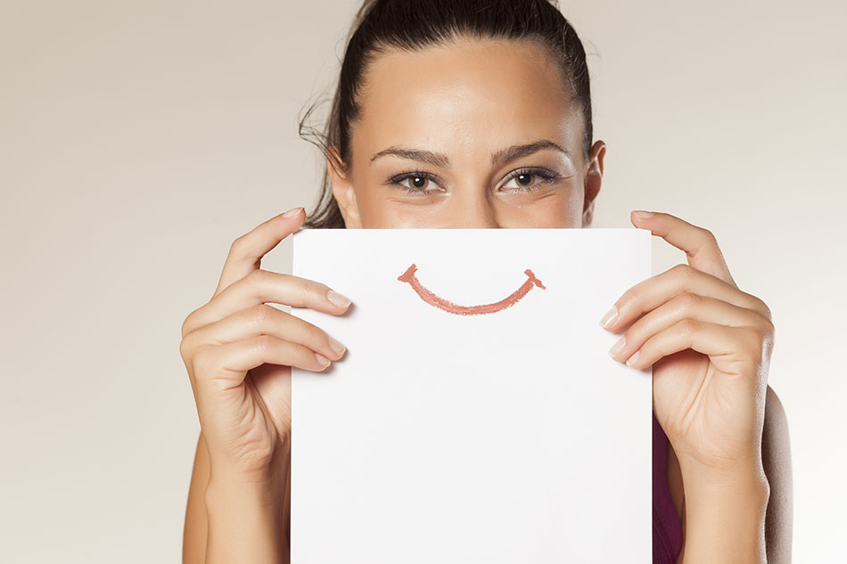 happy woman holding paper with smiley face in front