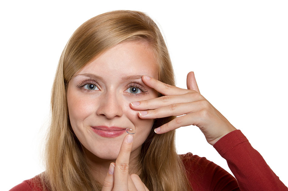 Woman putting in contact lens while holding eyelid and looking forward