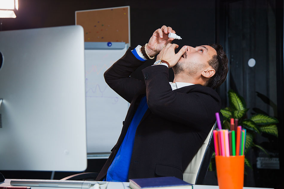 Male office worker using eye drops for dry eyes