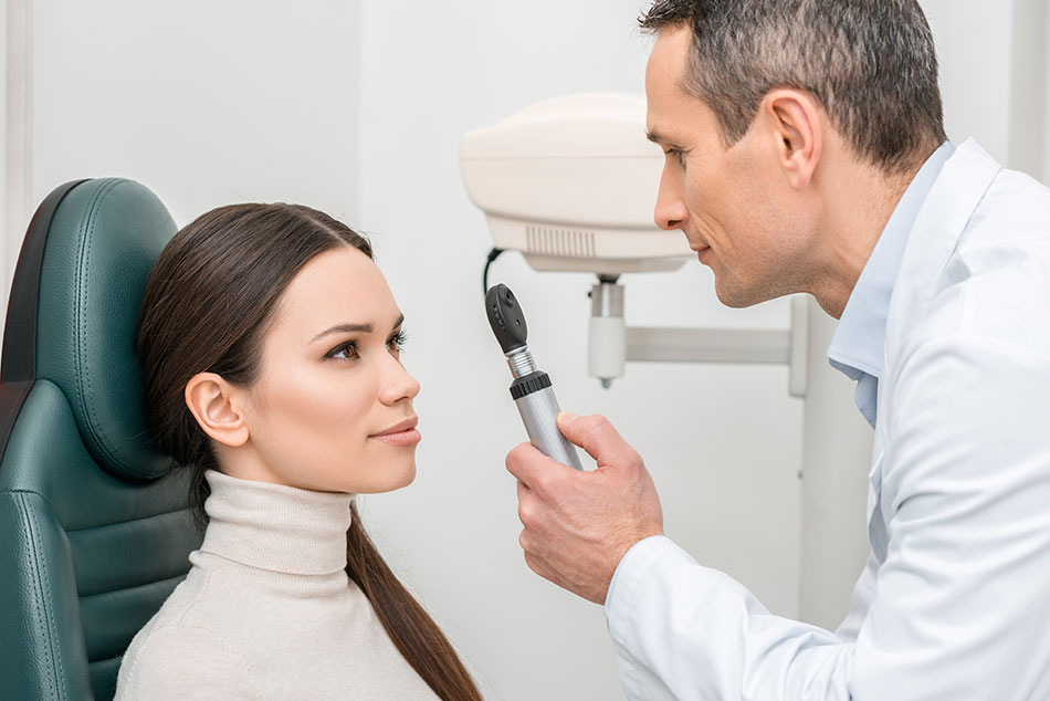 Male ophthalmologist checking female patient’s eyes