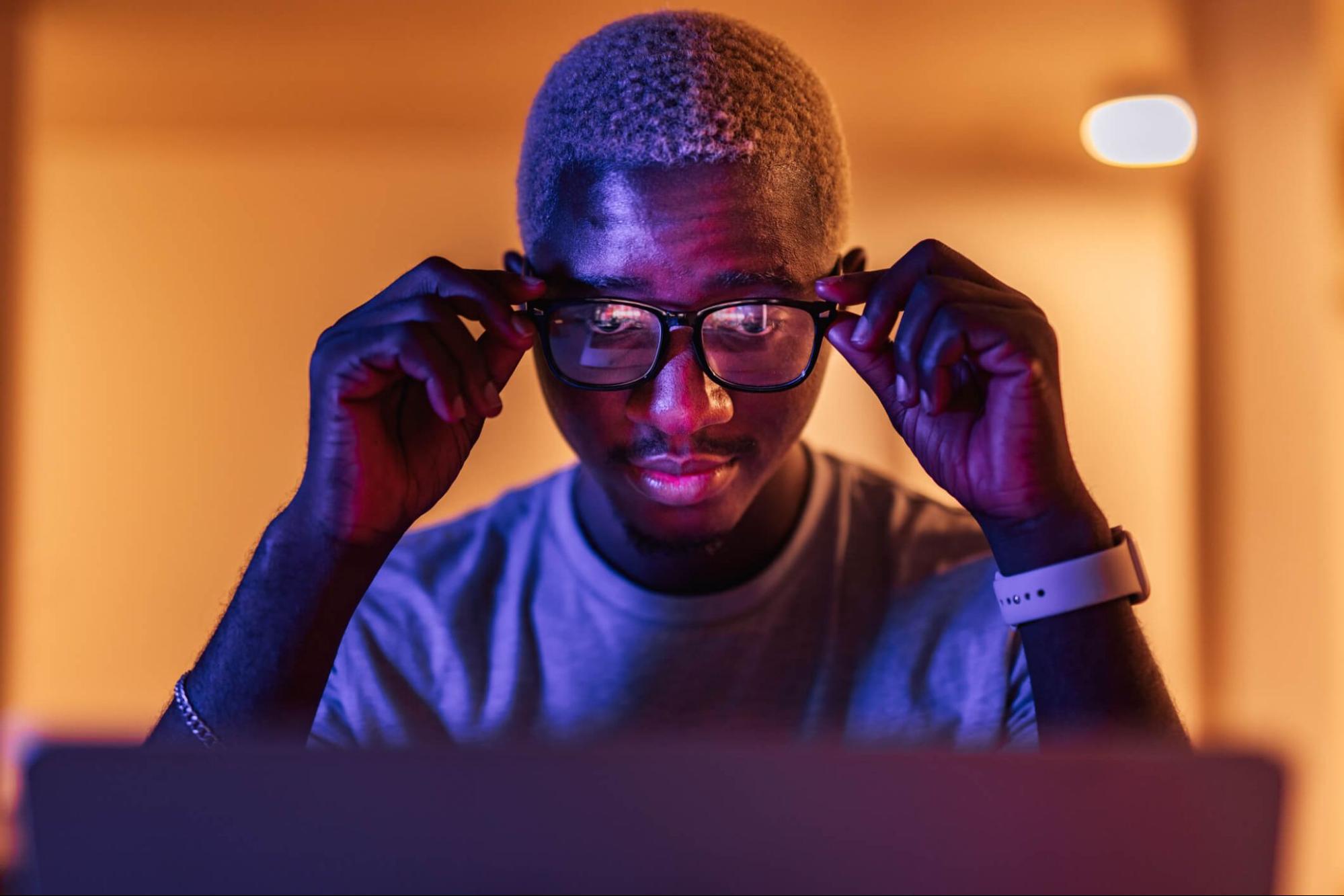 man adjusting glasses while looking at screen