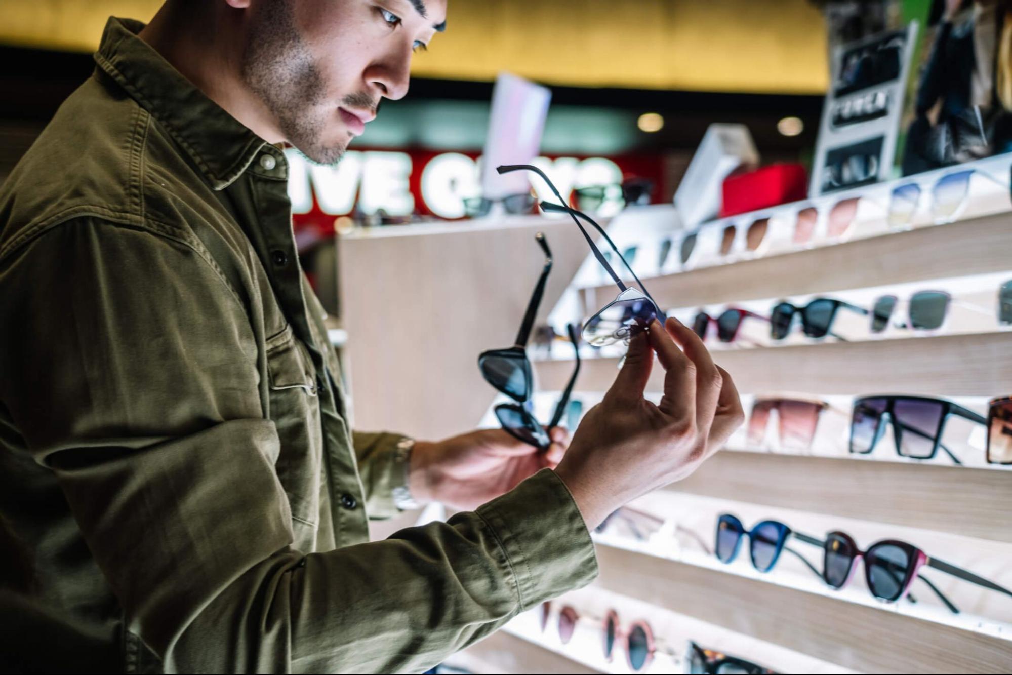 A man choosing sunglasses for UV protection in a store