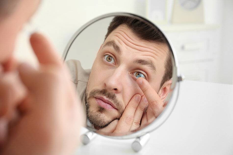 man showing how to put contacts in using mirror