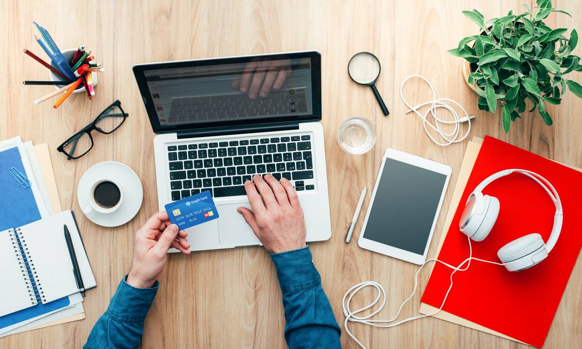 Man with credit card out shopping on laptop
