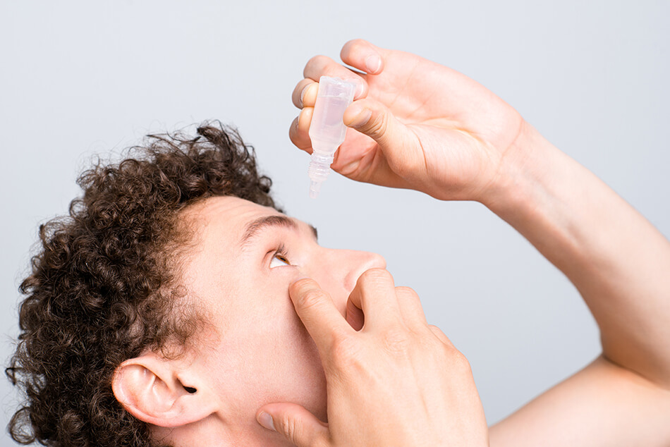 man putting eye drops in his eye