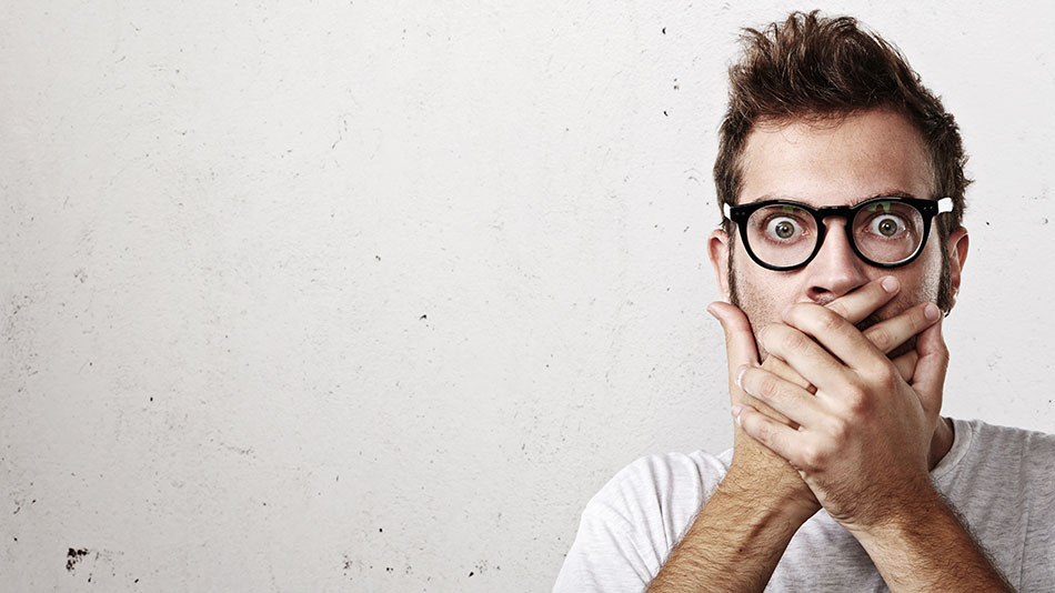 Man in glasses showing fear covering mouth with hands