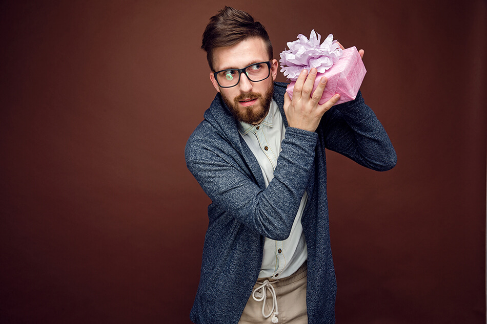 Man in glasses shaking a gift box