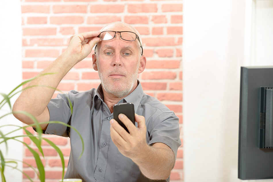 man with mobile phone has trouble reading the screen