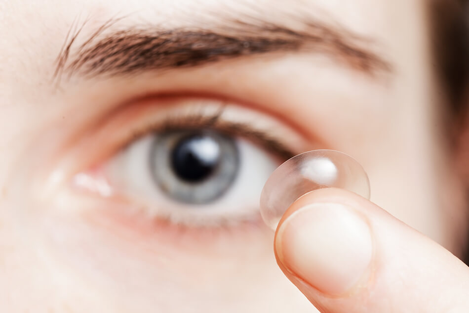 man inserting contact lens into his eye