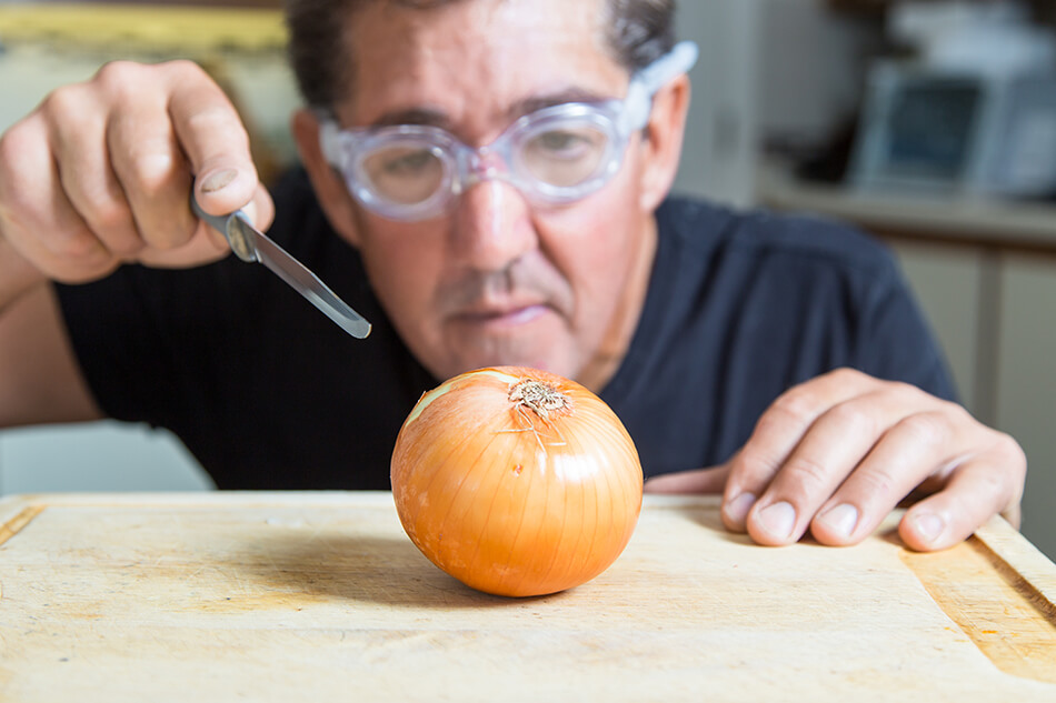 man wearing goggles while cutting an onion for good eye safety in the kitchen
