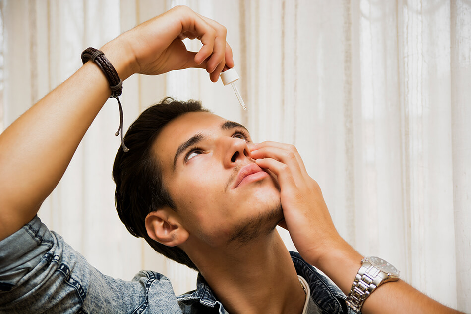 man using eye drops