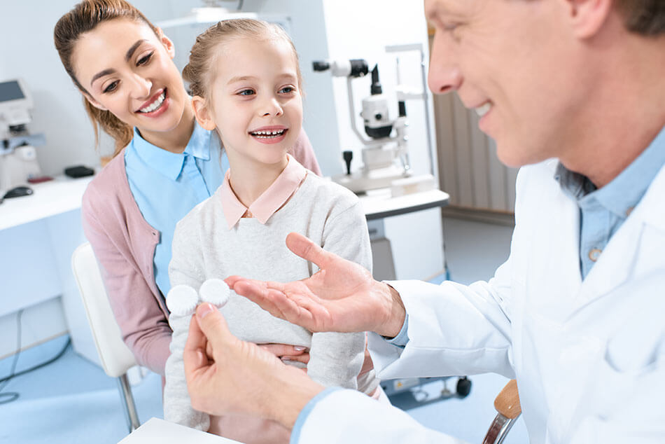 mom and little girl visit the eye doctor holding contacts lens case