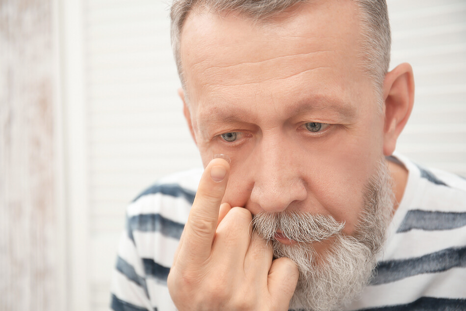 older man putting in contact lenses