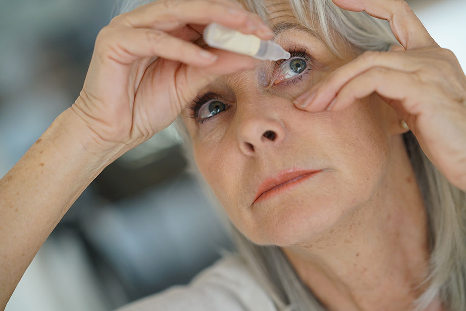 older woman putting drops in left eye