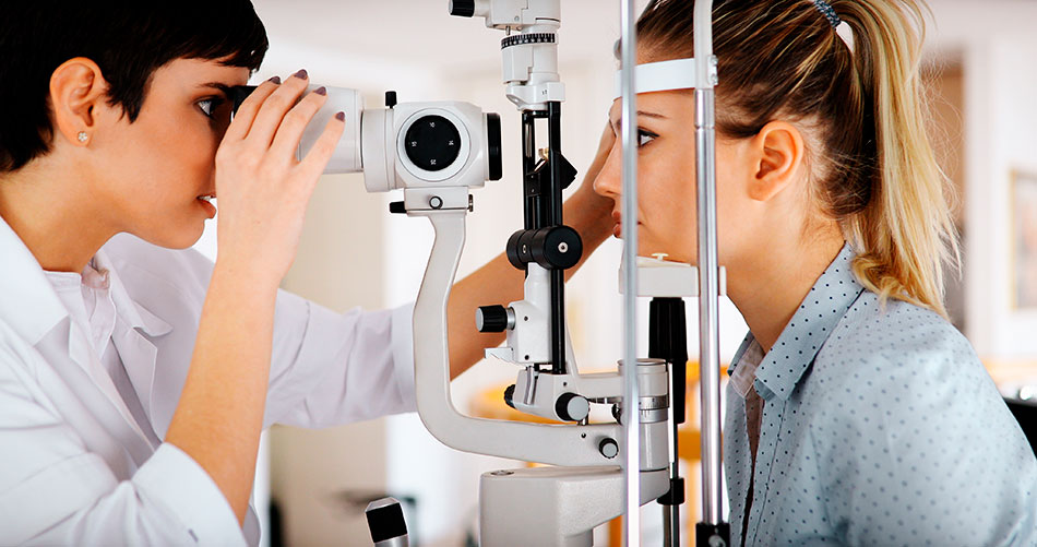 Optometrist using eye exam machine on patient