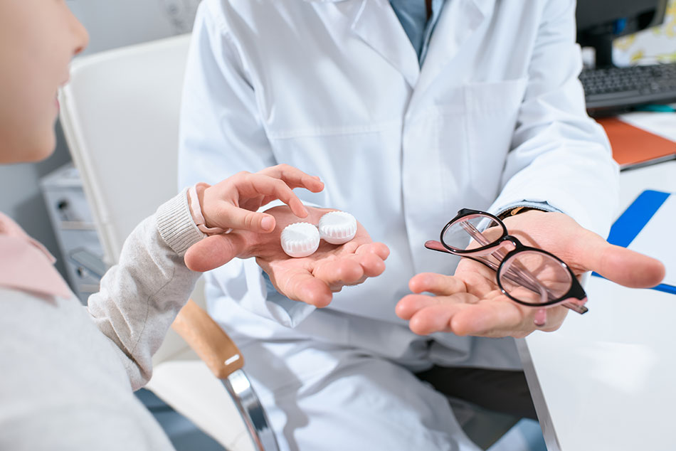 Optometrist offering glasses and contacts lenses to young girl