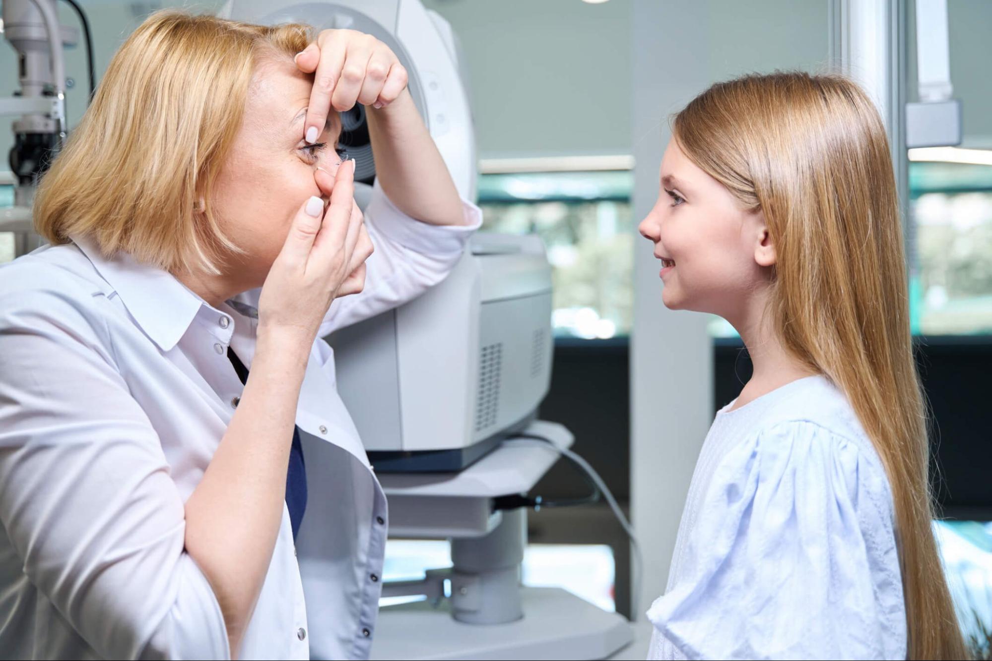 Optometrist showing a child how to insert a contact lens