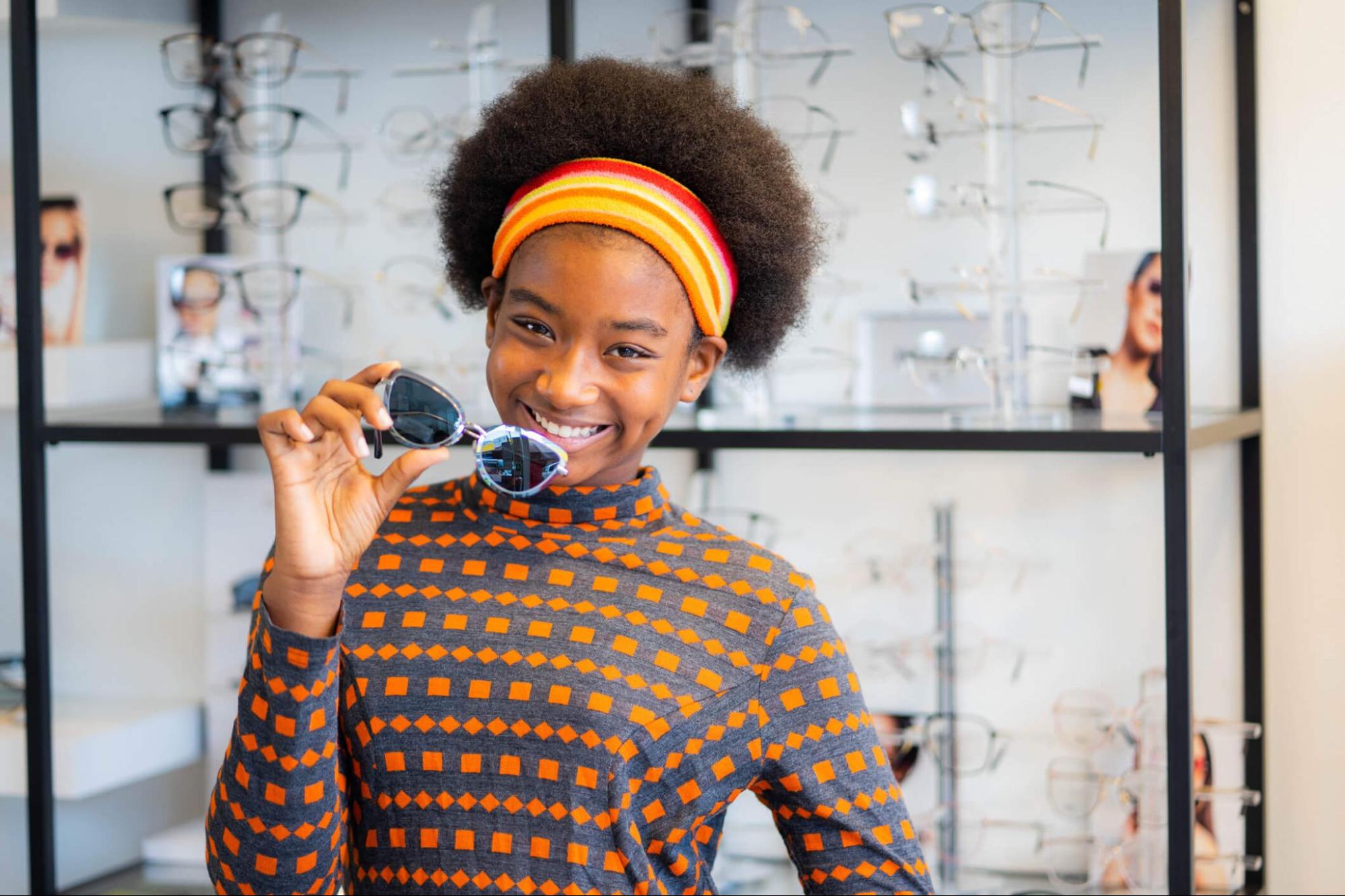 Pre-teen girl shopping for sunglasses for kids at an eyewear store