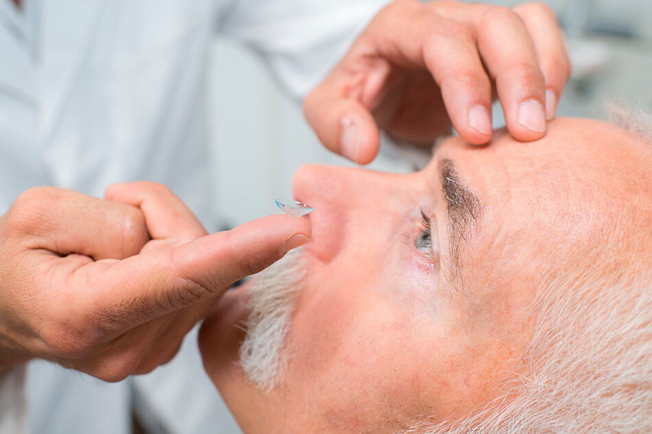 Senior man being taught how to put in contact lenses by a doctor