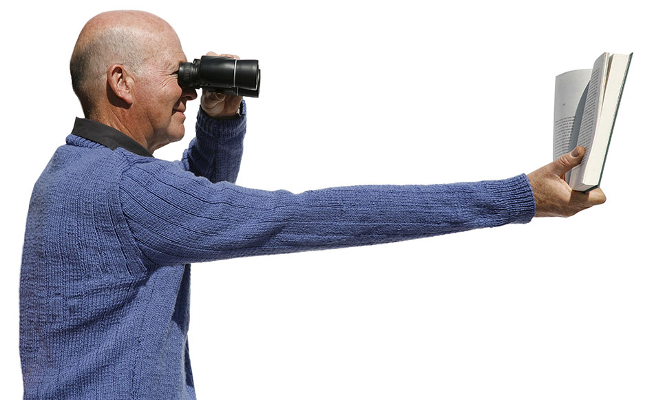 Senior man reading book with binoculars and arm stretched out